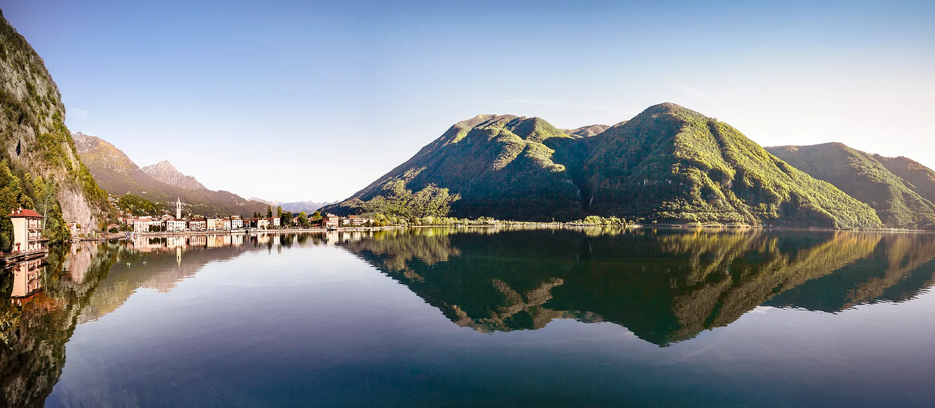 Riva del Lago di Lugano con spiaggia naturale e montagne, scenario ideale per vivere la natura ogni giorno a Porlezza.